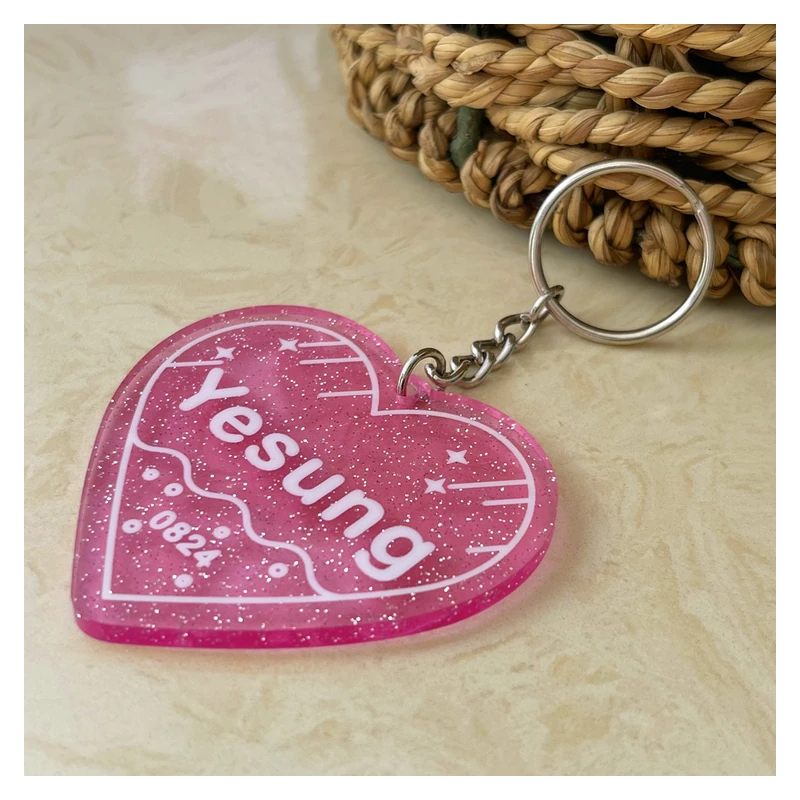 Pink heart-shaped acrylic keychain with glitter and white lettering.