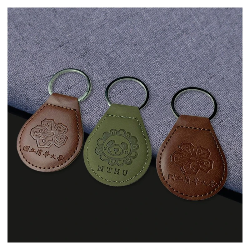Brown and green leather key tags with recessed lettering and decorative motifs.