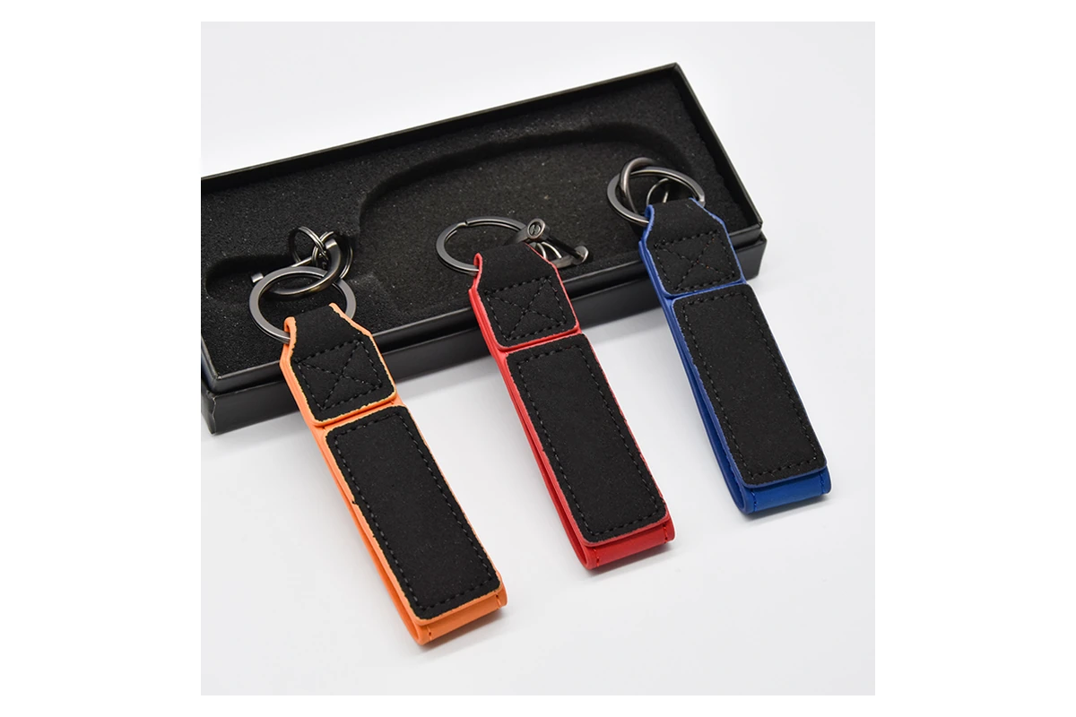 Black leather key straps with colored edges displayed beside an open black gift box.