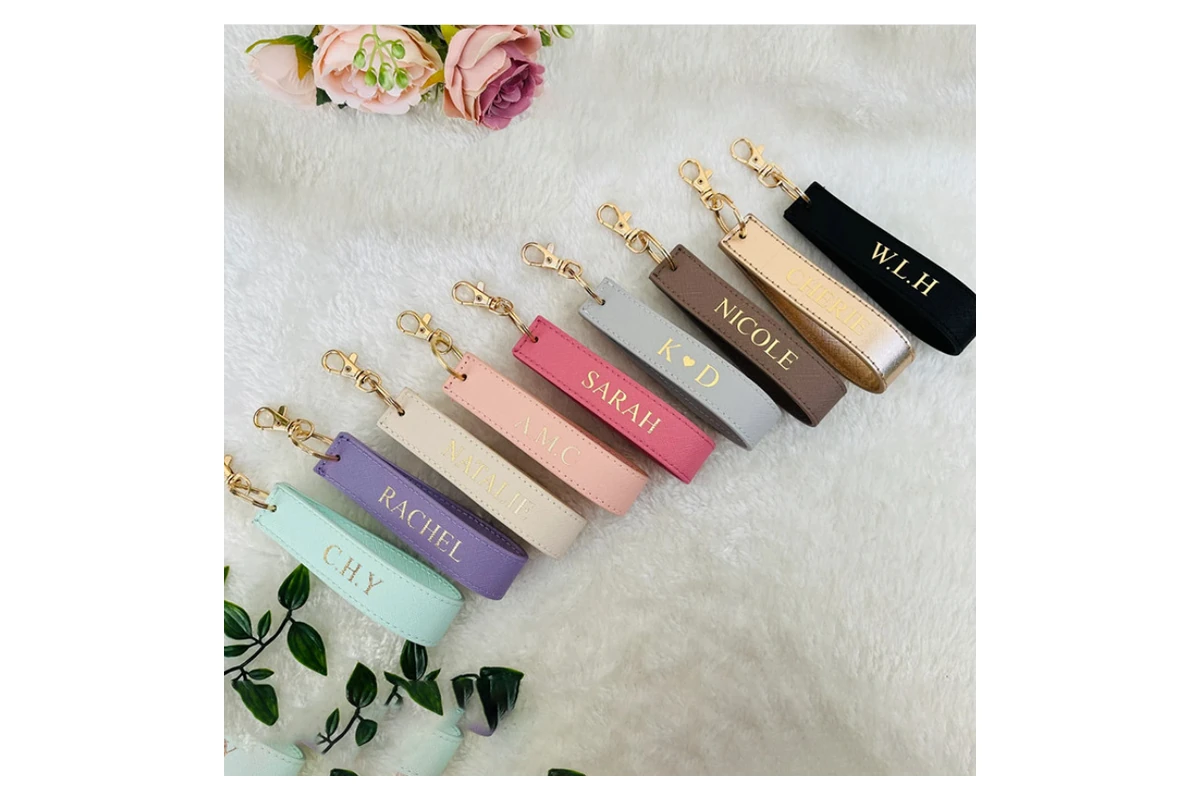Personalized leather straps with metallic names and gold-tone key fittings.