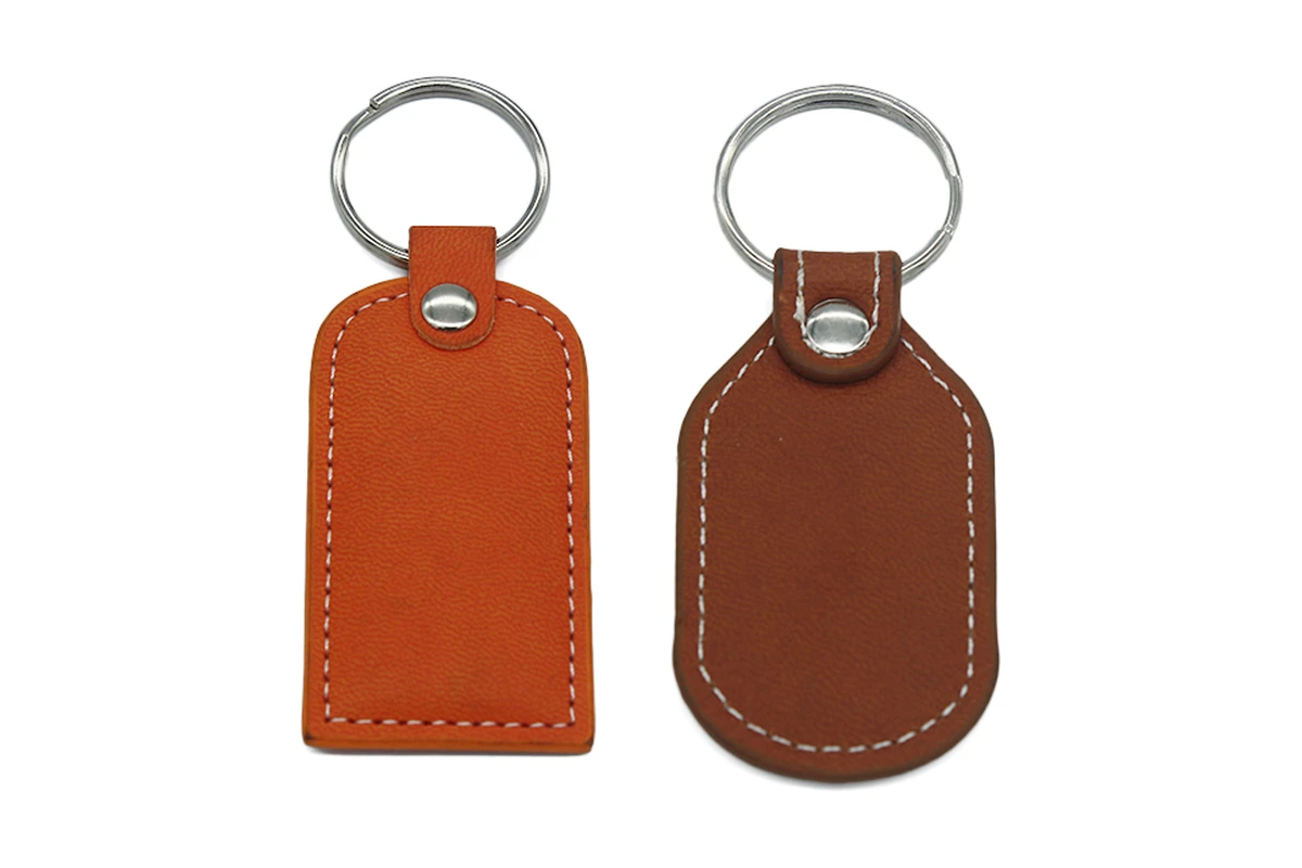 Brown and tan leather key tags with white stitching and silver-tone rings.