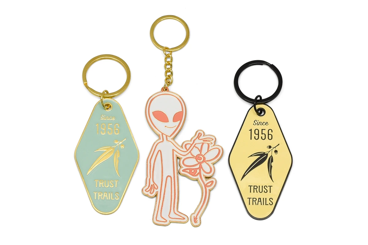Color-filled metal keychains with two motel-style tags and an alien holding a flower.