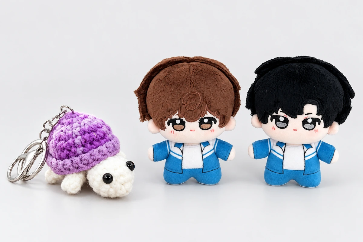 A purple crocheted turtle keychain beside brown-haired and black-haired plush dolls in blue outfits.