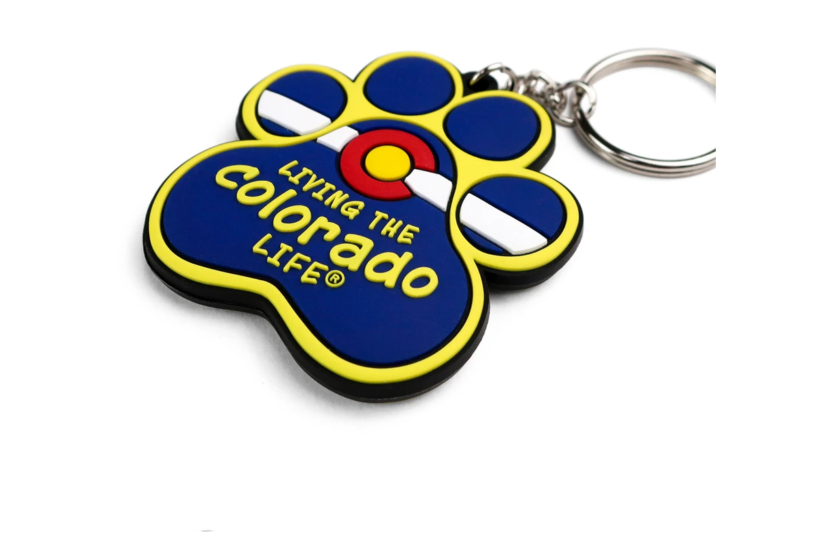 Blue and yellow paw-shaped PVC keychain with raised lettering.