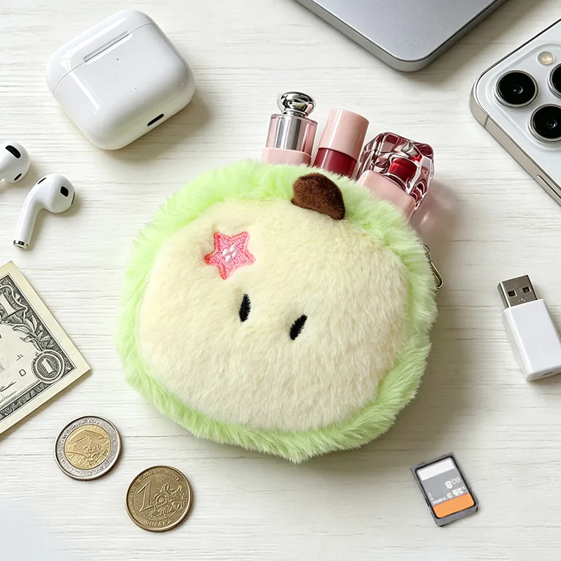 Green plush apple coin purse with a cream center, pink star, and cosmetics tucked inside.