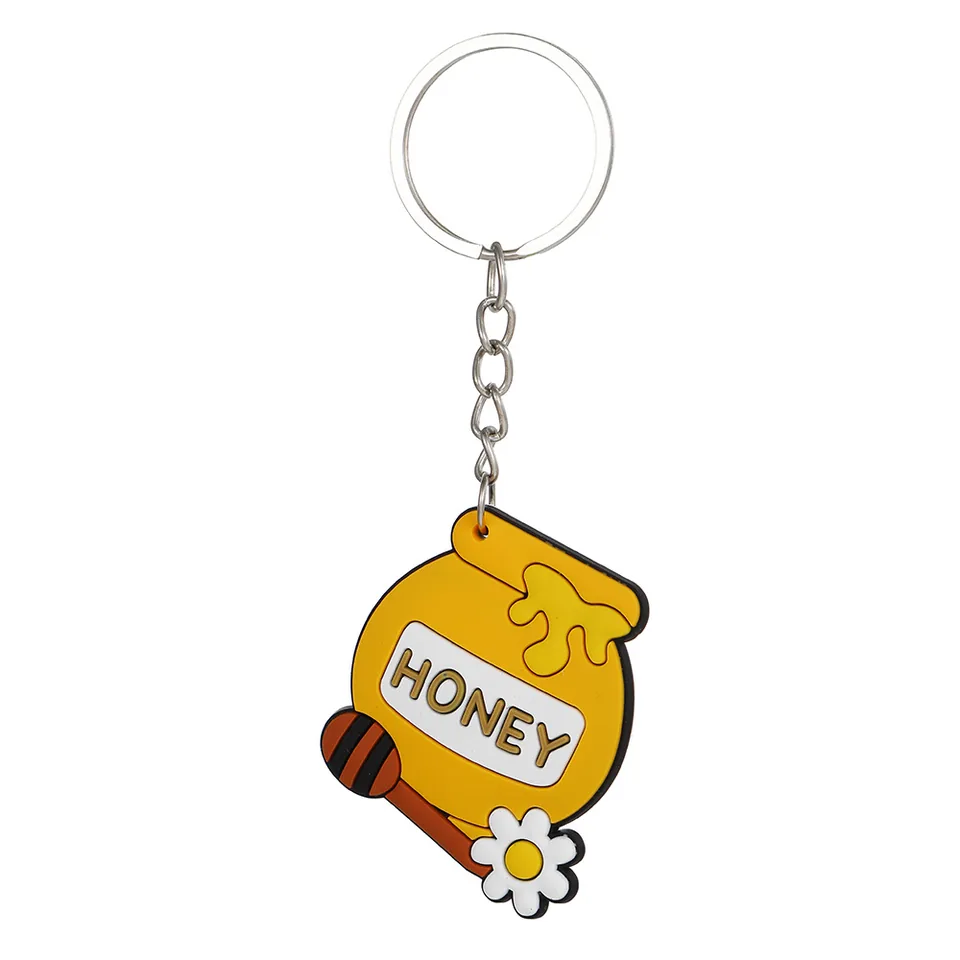 Yellow honey jar keychain with HONEY lettering, a honey dipper, and a white flower.