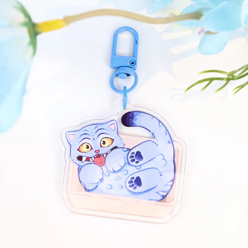 Blue cartoon cat keychain with yellow eyes, purple paw pads, and a blue swivel clasp.