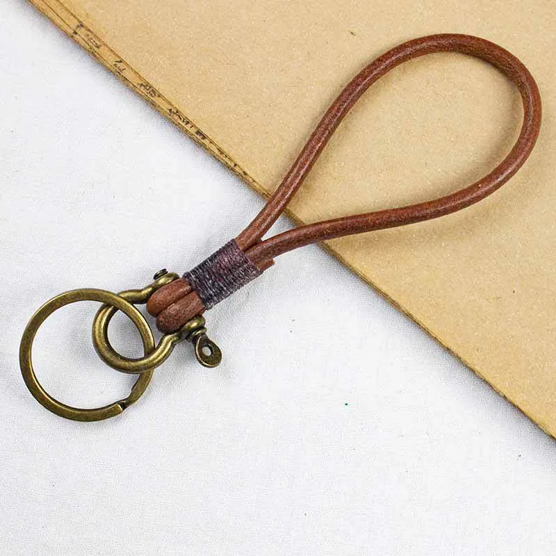 Brown cord wrist loop with a wrapped join, bronze-tone rings, and a small clip.