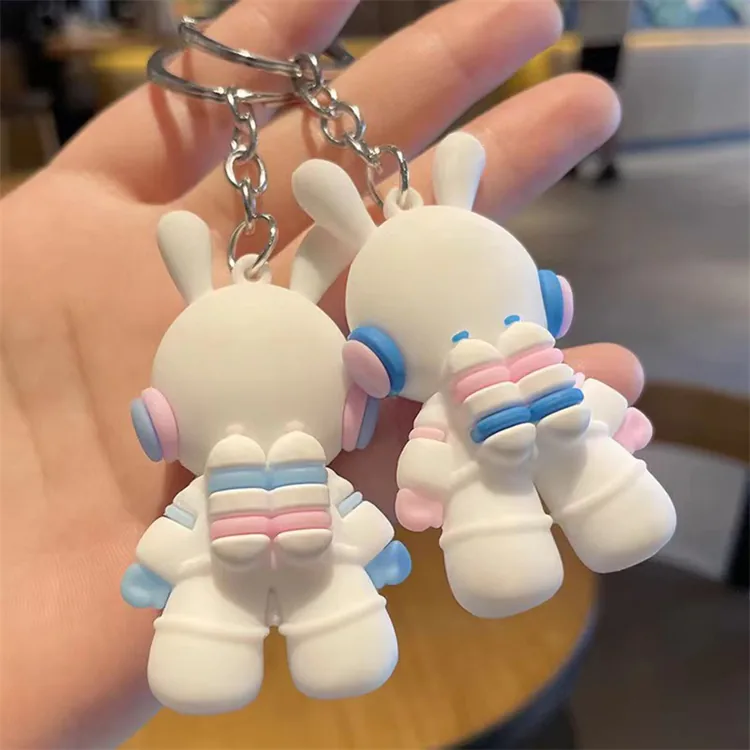 Rear view of white bunny astronaut keychains with pink and blue backpack details.