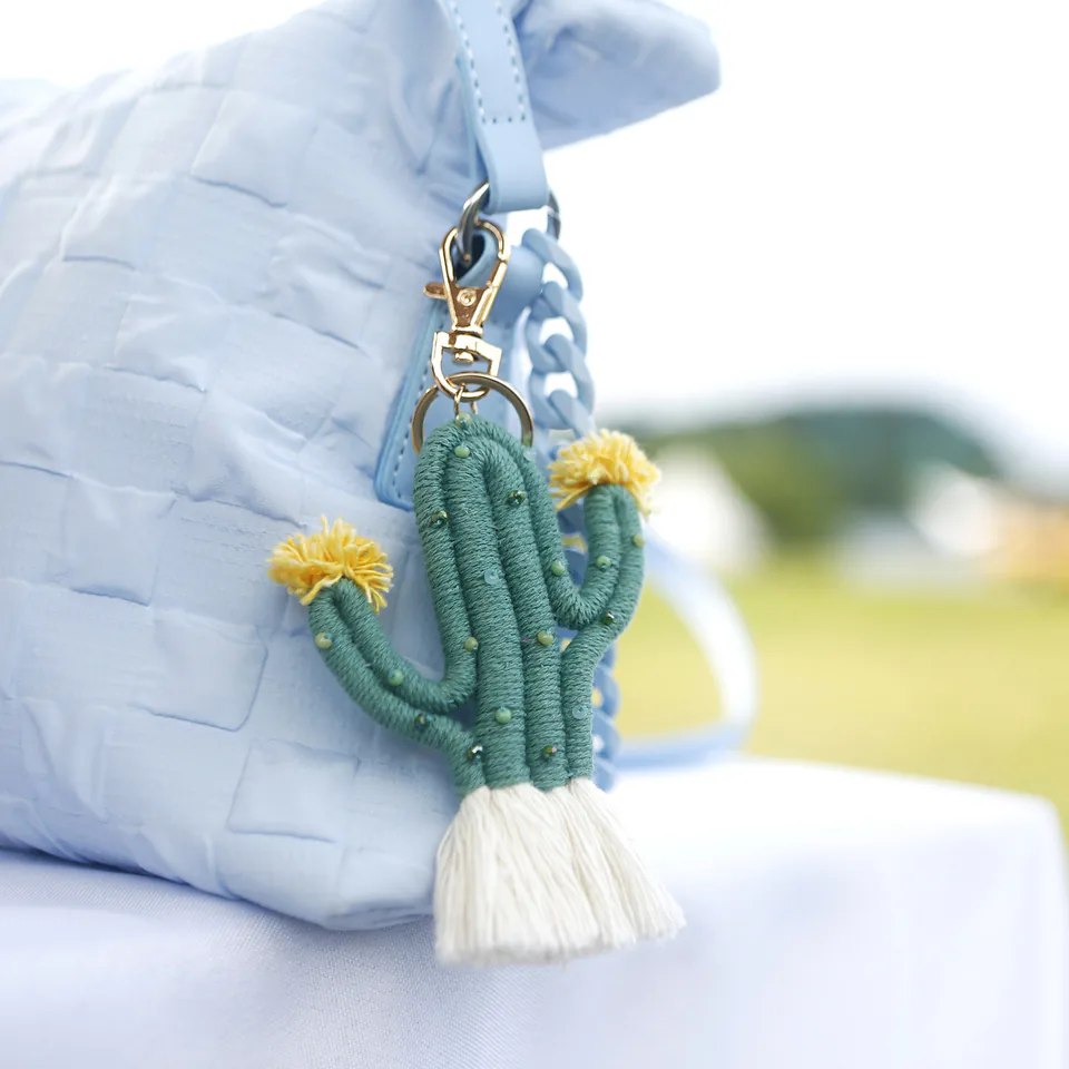 Green cactus keychain with yellow flowers, small knotted details, and a white tassel.