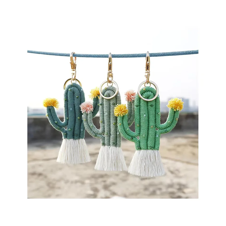 Three green cactus keychains with yellow and pink flowers and white tassels.