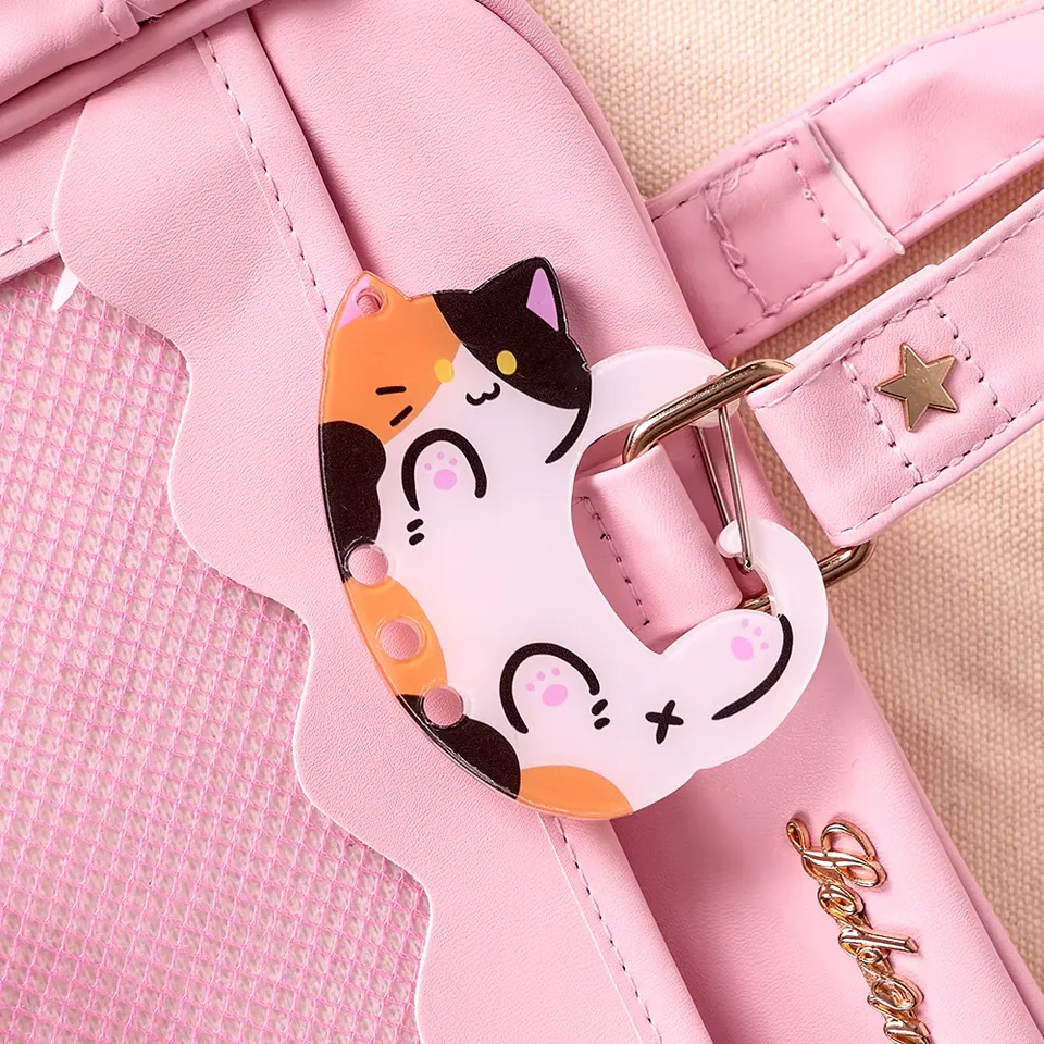 Calico cat clip with pink paw details attached to a pink bag strap.