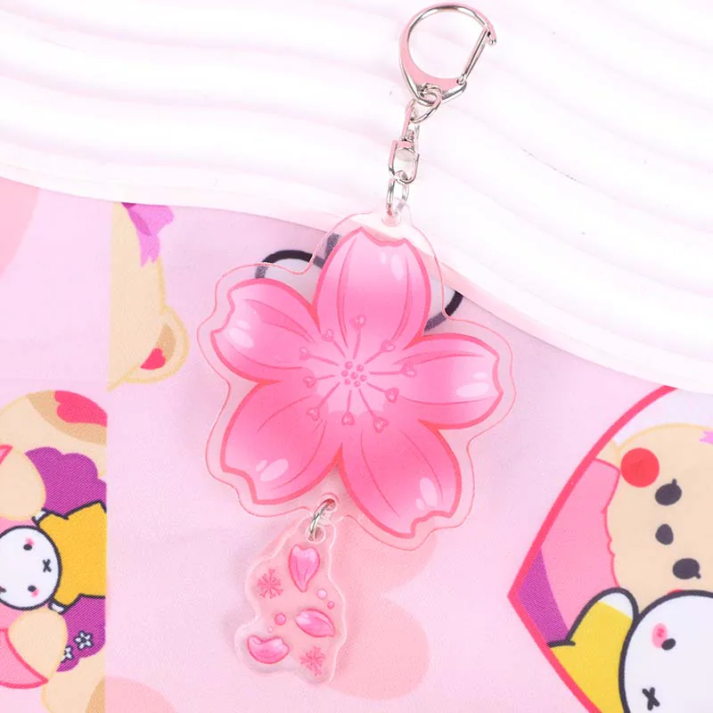 Pink cherry blossom keychain showing outlined petals and a clear dangling charm.