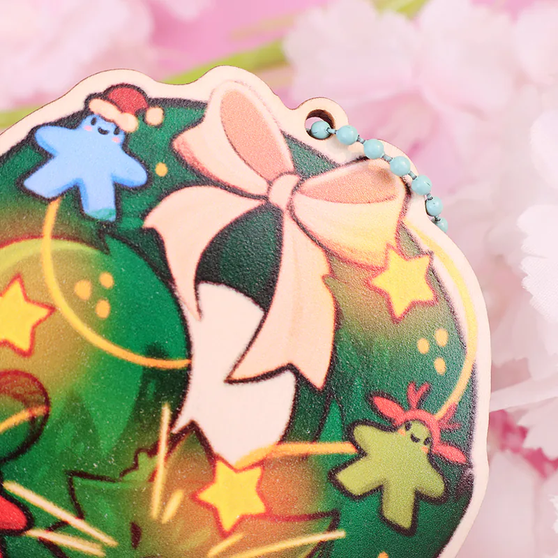 Close-up of the pink bow and yellow stars on a green Christmas wreath keychain.