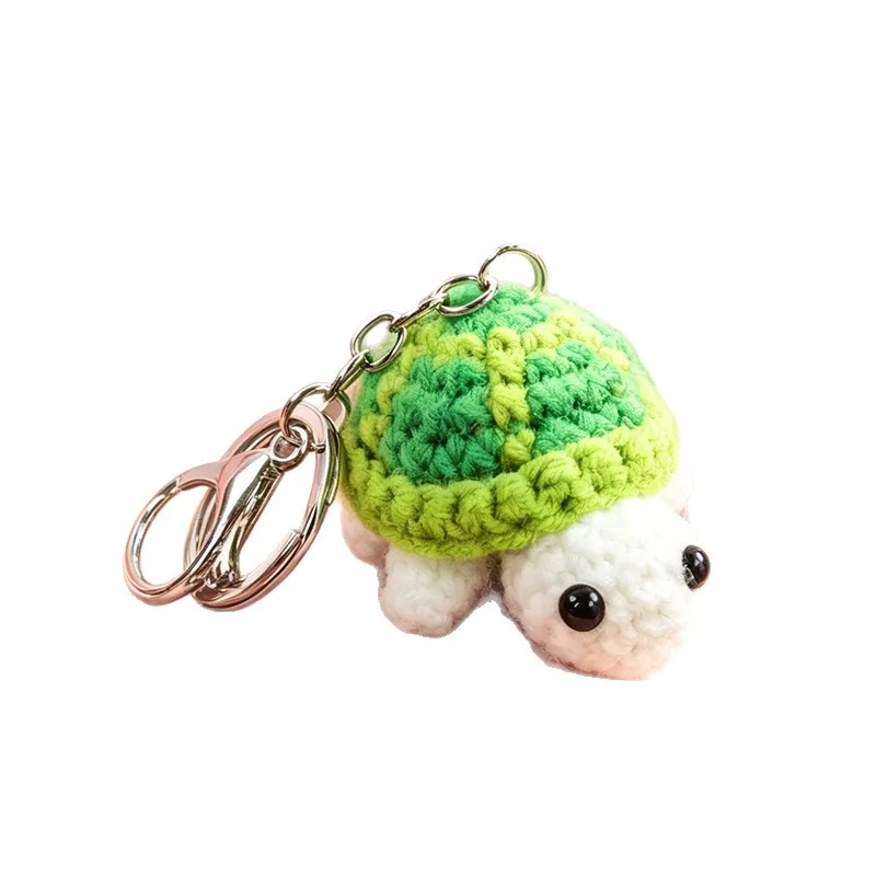Crochet turtle keychain with a green shell, cream body, and black bead eyes.