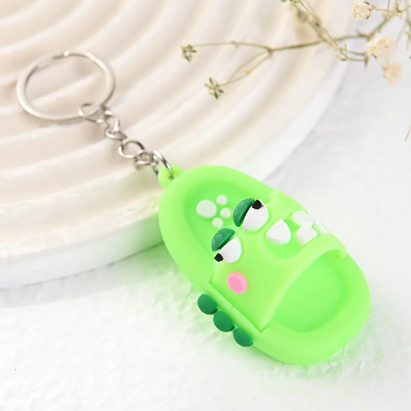 Green crocodile slipper keychain with white teeth and pink cheeks.