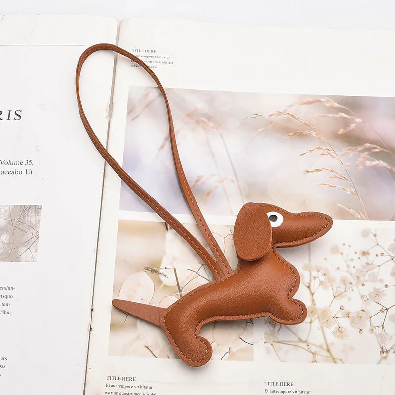 Brown dachshund charm with a long body, floppy ears, stitched edges, and a cord loop.
