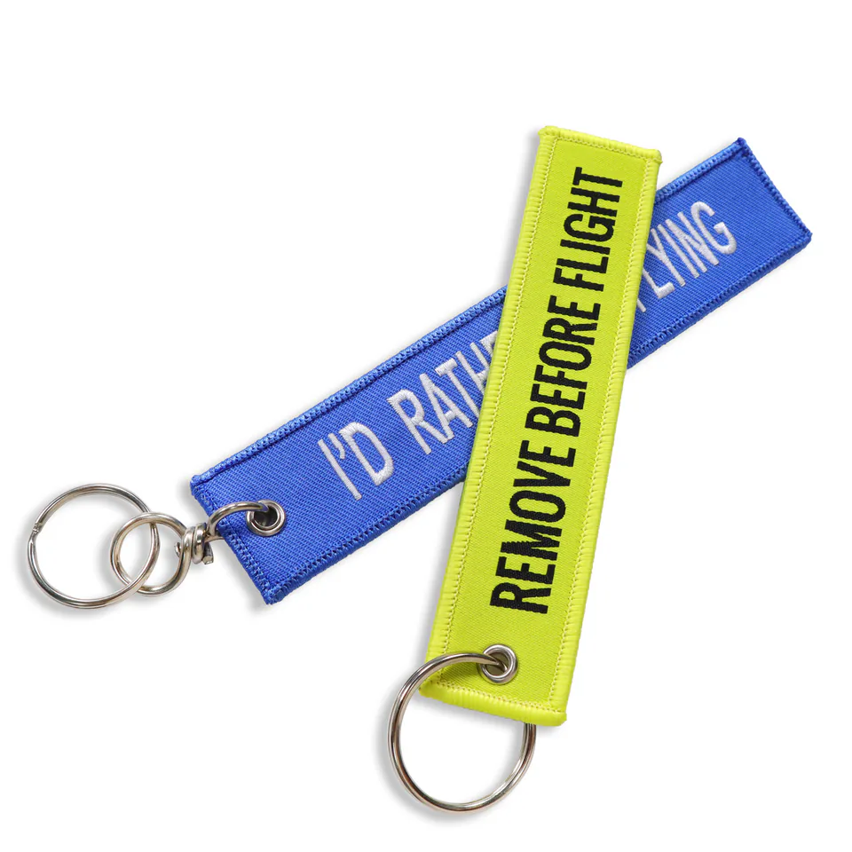 Crossed blue and neon yellow flight tag keychains with stitched lettering and silver-tone rings.