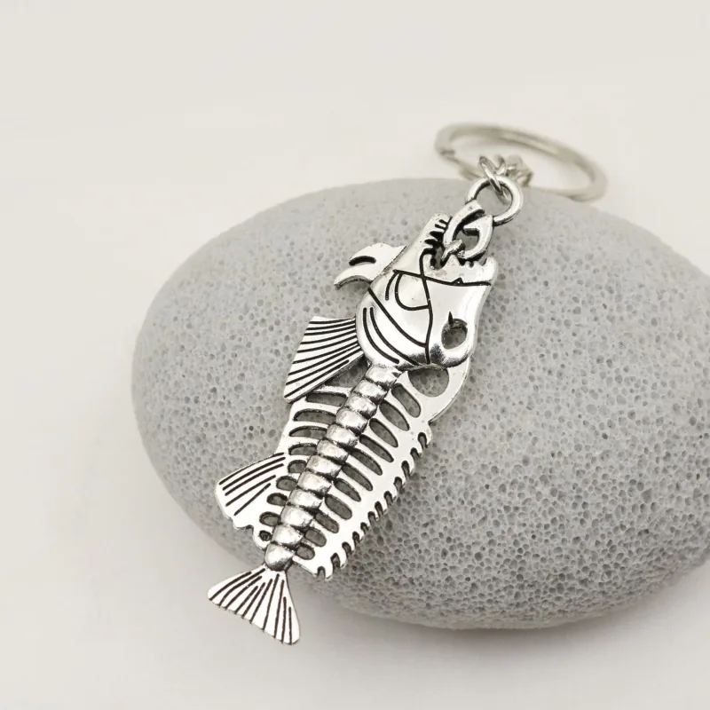 Silver-tone fish skeleton keychain with cutout ribs and a fan-shaped tail.