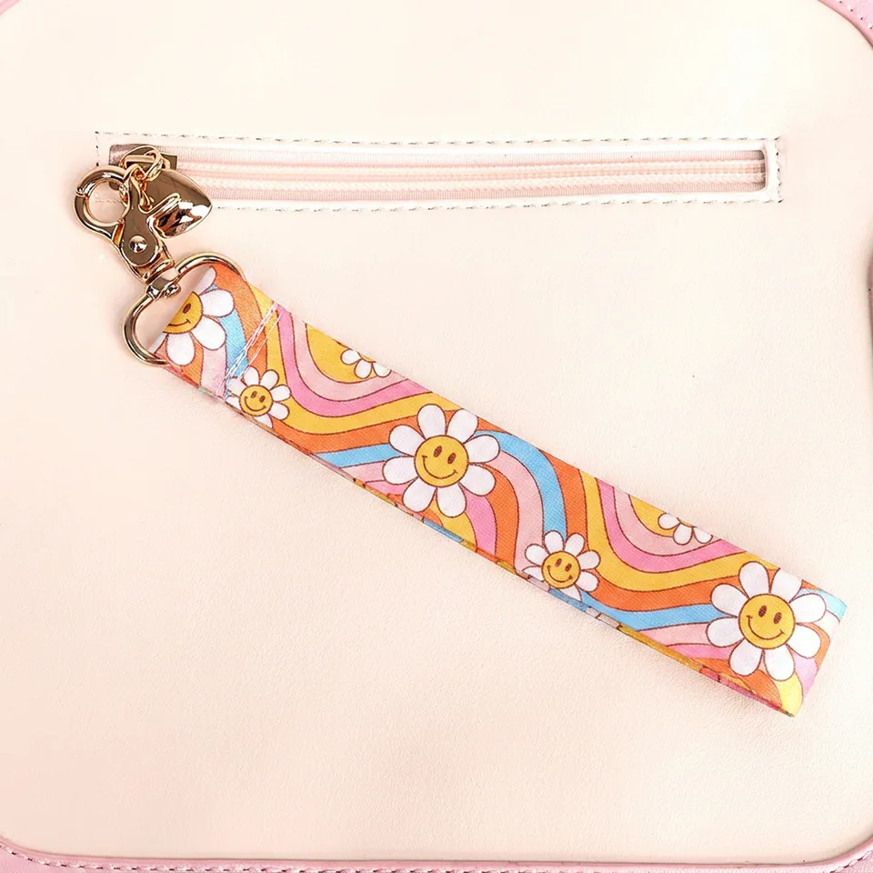 Floral wristlet keychain clipped to a bag, with white daisies and colorful stripes.
