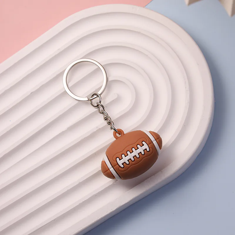 Brown football-shaped keychain with white laces and end stripes.