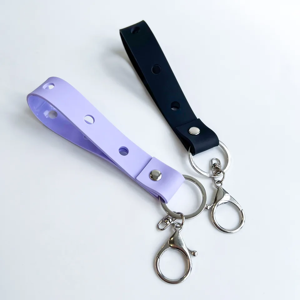 Lavender and black keychain straps with round charm holes and silver-tone clasps.