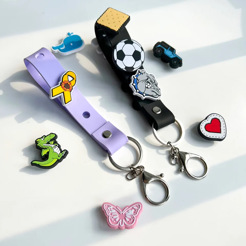 Lavender and black keychain straps decorated with small charms, with loose charms alongside.
