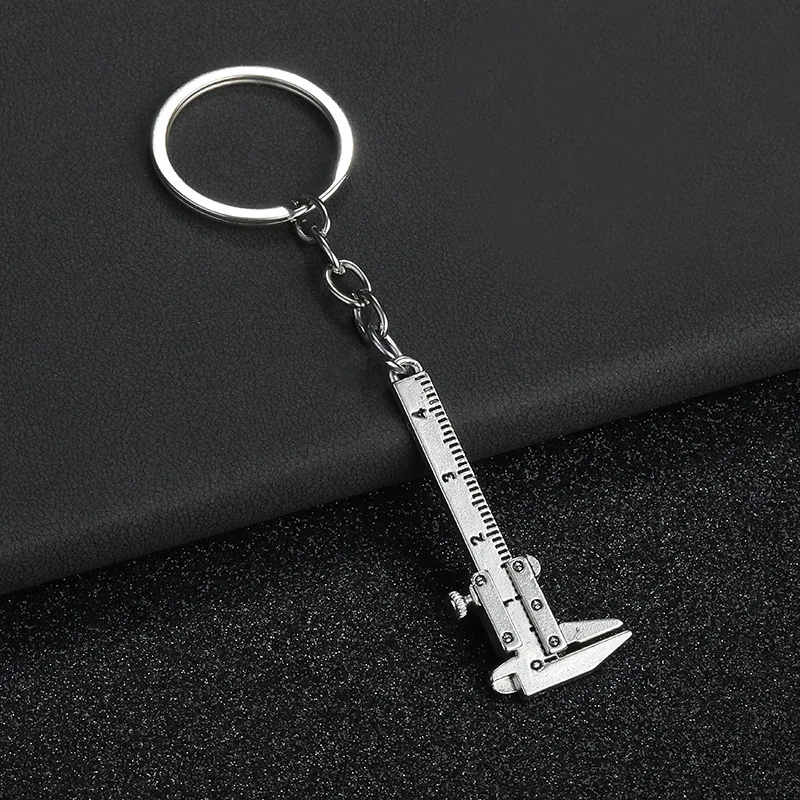 Silver-tone miniature caliper keychain with a numbered scale and closed jaws.