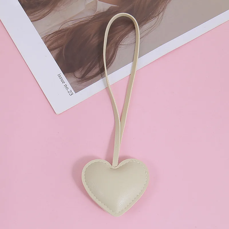 Cream padded heart charm with stitched edges and a long matching loop.