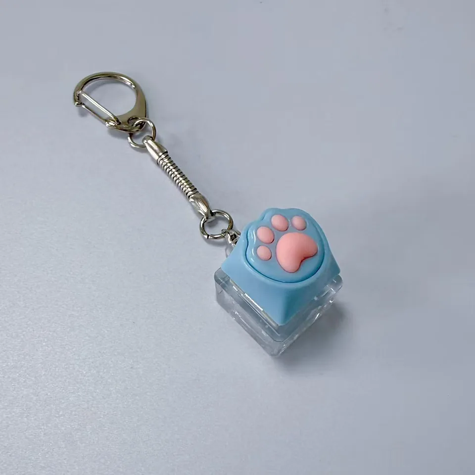 Blue keycap keychain with raised pink paw pads, a clear base, and a silver-tone clasp.