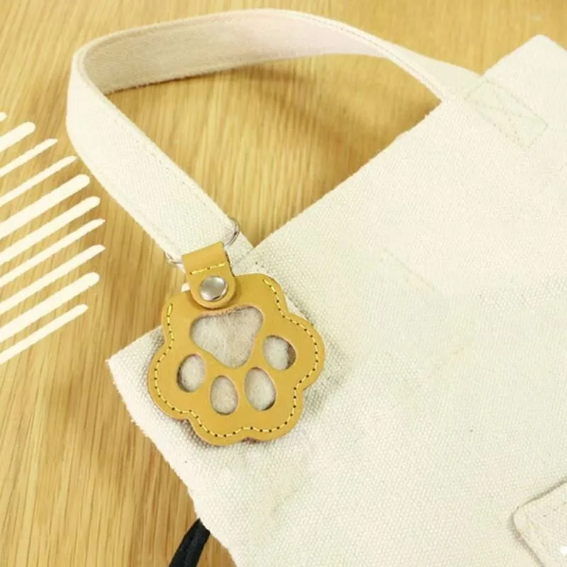 Yellow paw-shaped keychain with clear paw-pad windows attached to a tote bag.