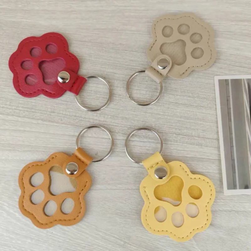 Red, cream, tan, and yellow paw-shaped keychains with clear windows and silver-tone split rings.