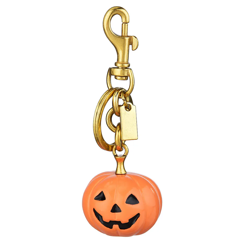 Orange jack-o’-lantern keychain with a gold-tone clasp and rectangular tag.