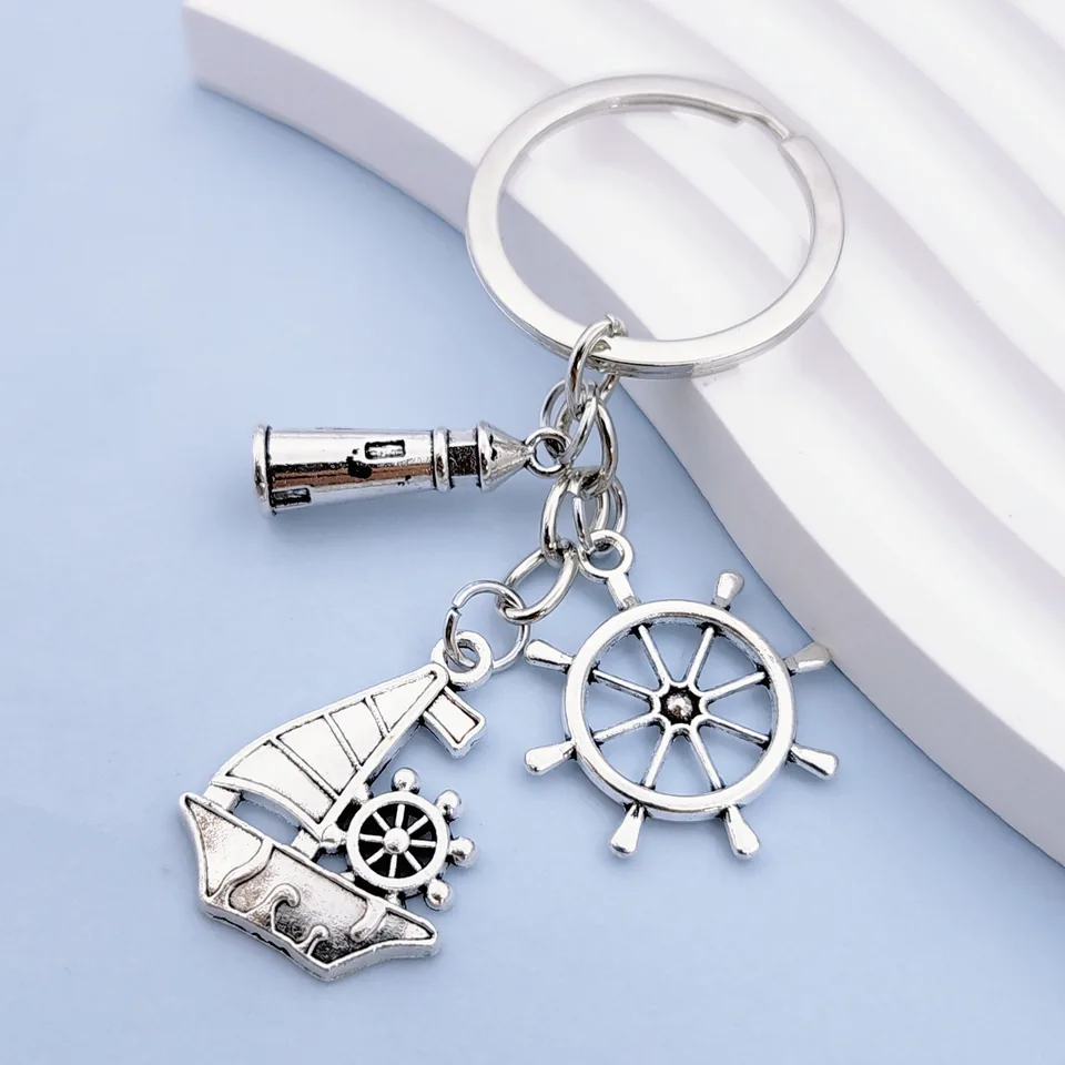 Silver-tone nautical keychain with sailboat, ship's wheel, and telescope charms.