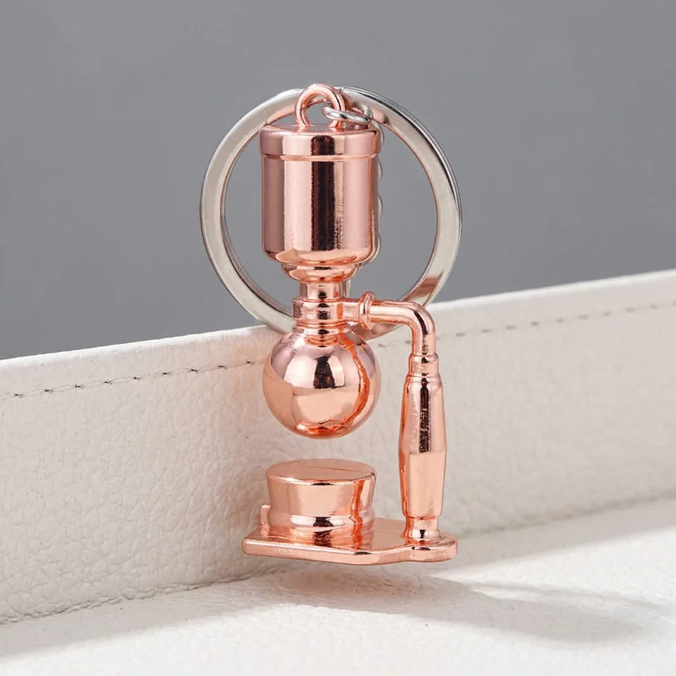 Rose-gold-tone miniature siphon coffee maker keychain shown from the front.
