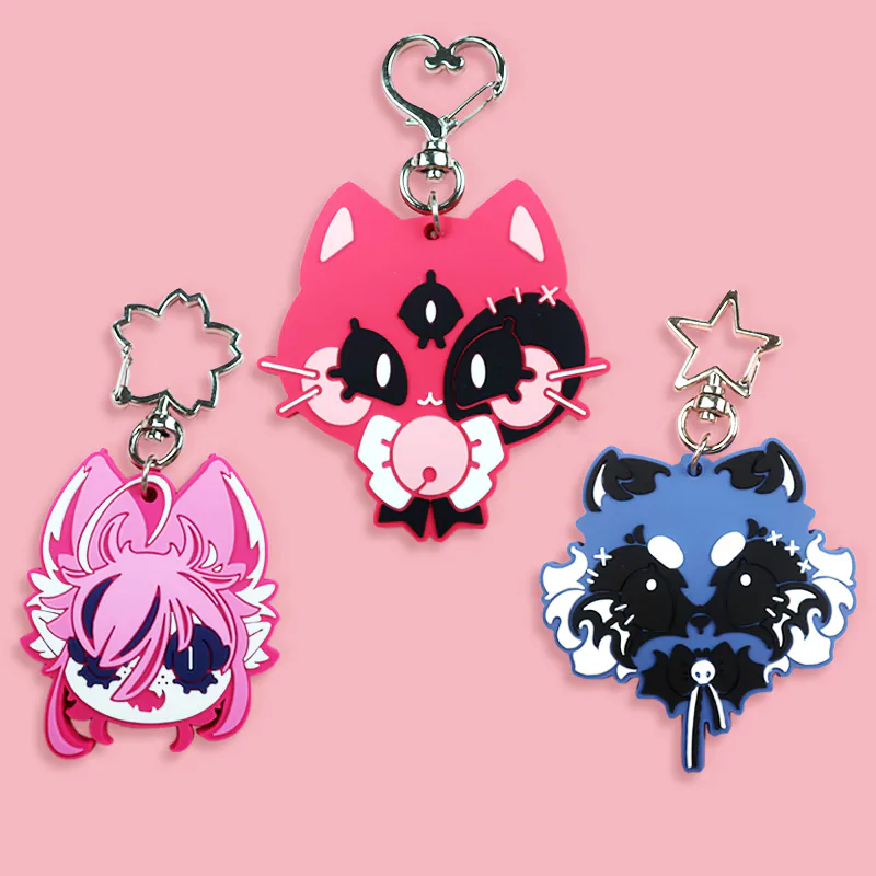 Hot pink three-eyed cat keychain displayed with pink and blue character charms.