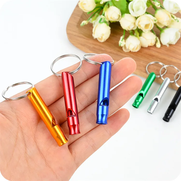 Gold, red, and blue tube whistle keychains held in a hand.