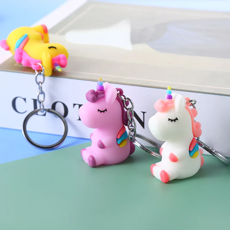 Purple, white, and yellow unicorn keychains with rainbow horns and tails.