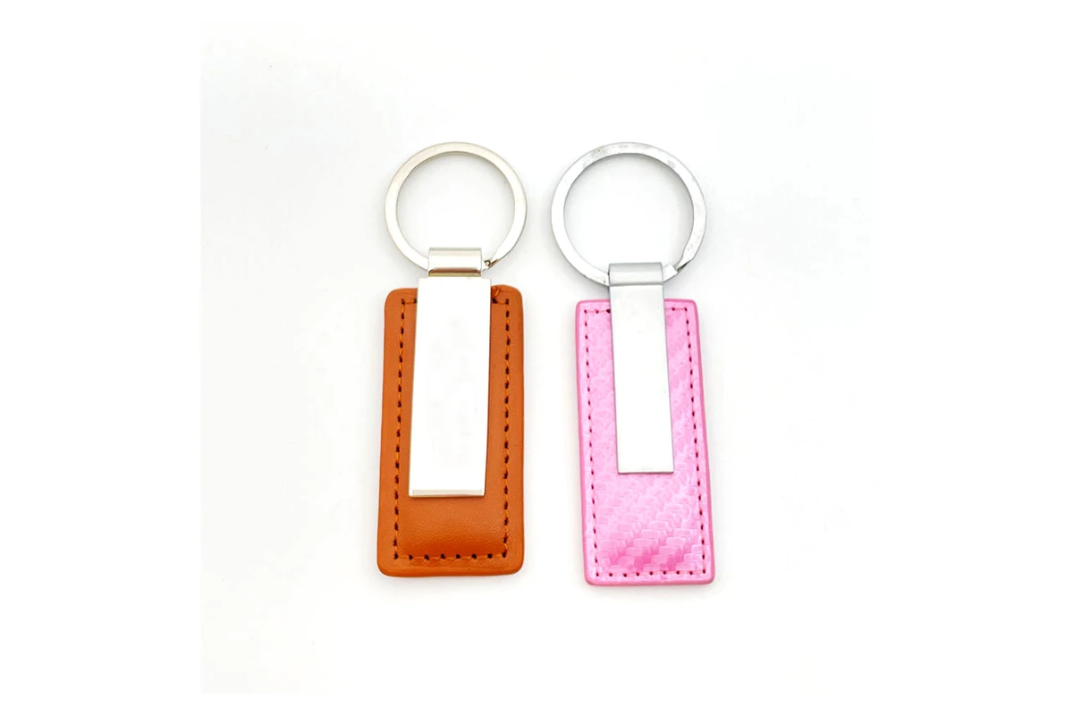 Orange and pink stitched key fobs with metal plates and split rings.