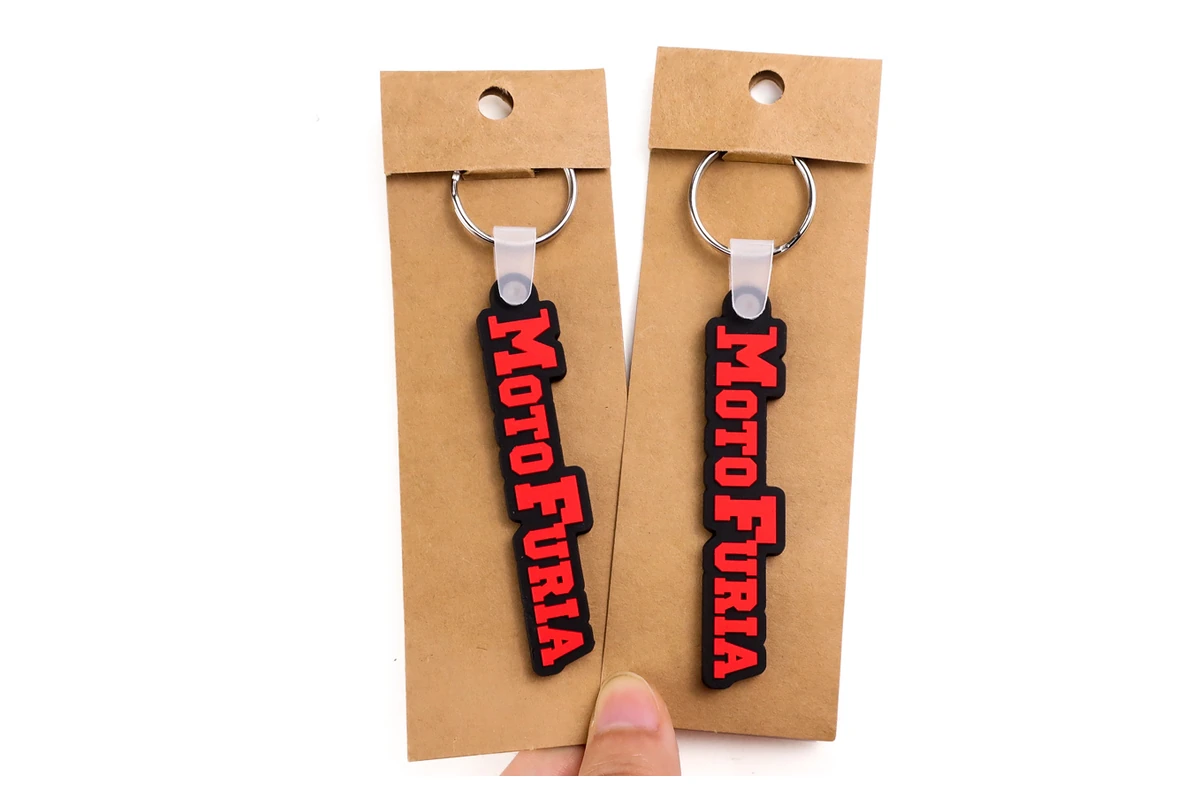 Red and black PVC logo keychains mounted on kraft display cards.